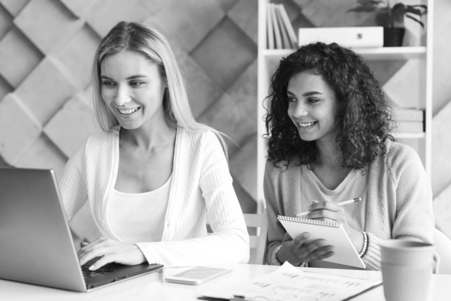 Modern classroom setup with laptops, whiteboards covered in business diagrams, and collaborative workspace arrangement
